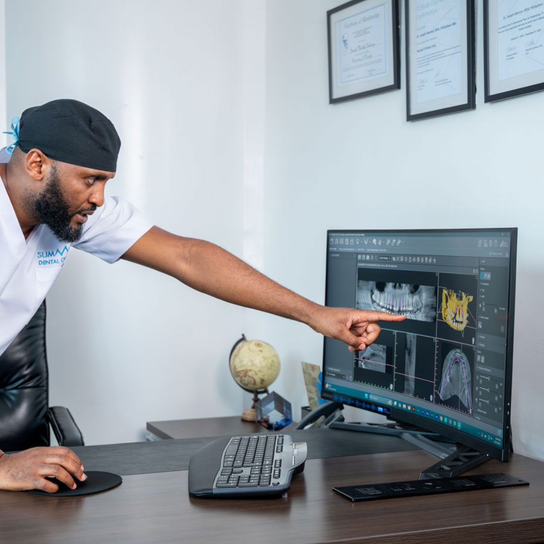 Doctor Joseph Gakonyo reviewing a CBCT scan image on a computer.