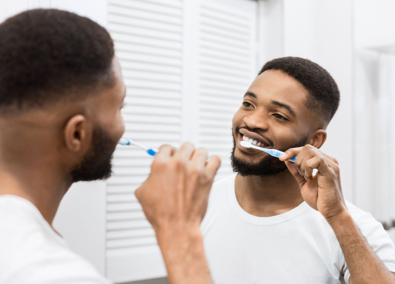 A reflection of a man brushing his teeth in front of a mirror
